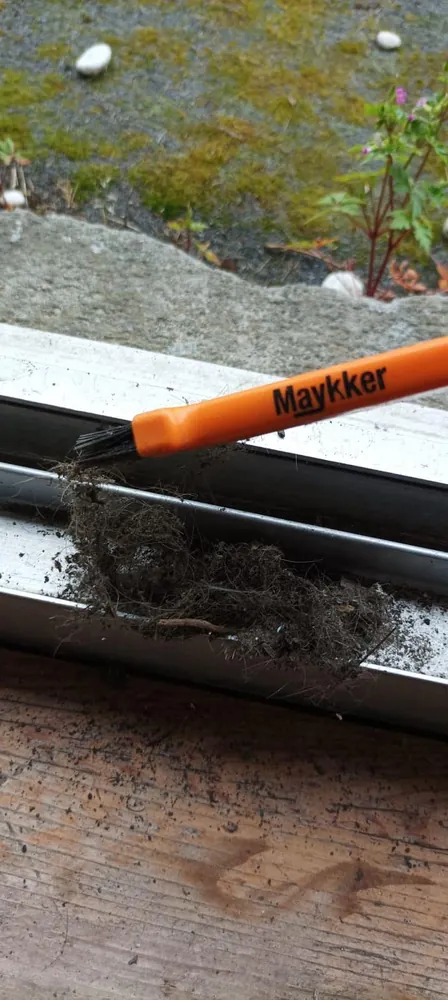 Schmutz wird mit einer Bürste aus der Fensterschiene entfernt